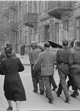 Powstańcy niosący zasobnik zrzutowy na ulicy Wojciecha Górskiego