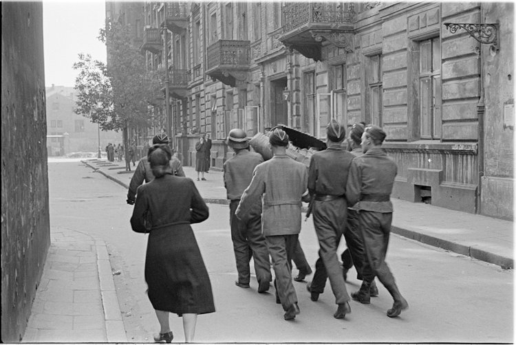 Powstańcy niosący zasobnik zrzutowy na ulicy Wojciecha Górskiego