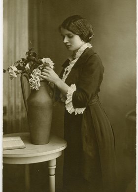 Portret młodej kobiety układającej kwiaty w wazonie