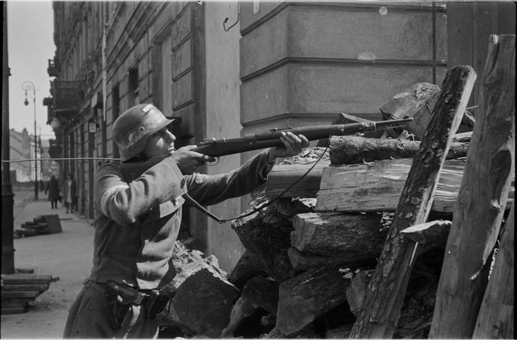 Powstaniec z karabinem na barykadzie