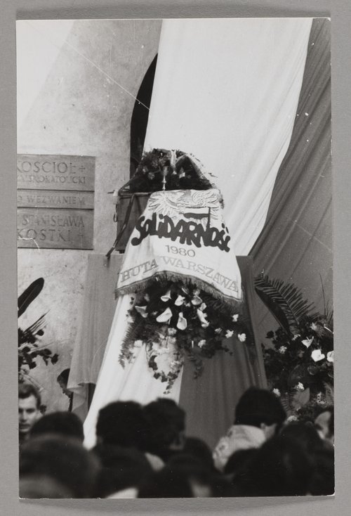 Pogrzeb bł. ks. Jerzego Popiełuszki - katafalk ze zwłokami kapłana otoczony chorągwiami, wieńcami i wiązankami kwiatów