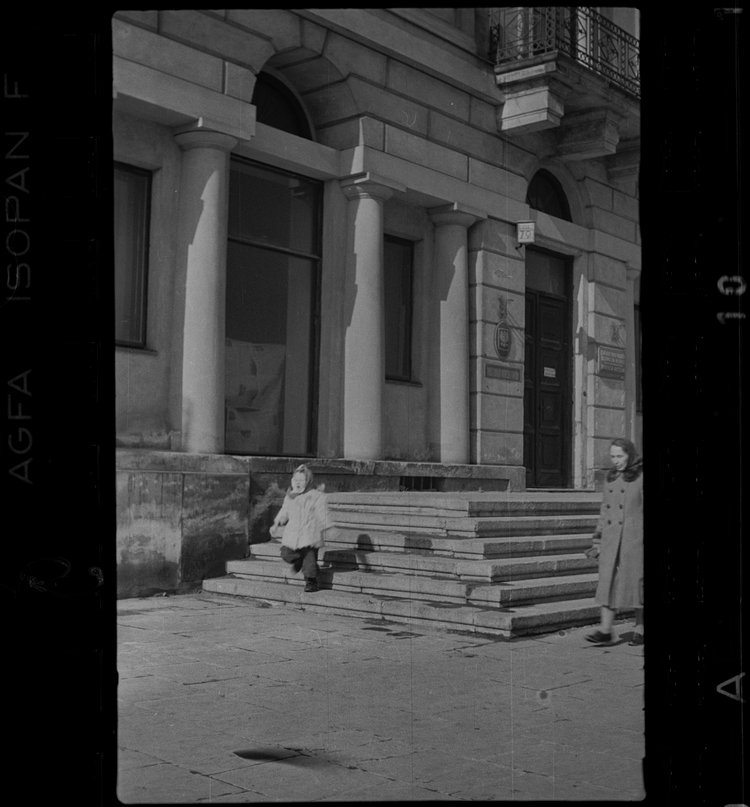 Matka z dzieckiem przy schodach przed kamienicą Roeslerów i Hurtiga