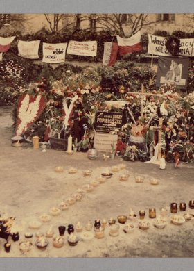 Grób bł. ks. Jerzego Popiełuszki, który został usłany wieńcami i wiązankami, a przed nim ustawiono znicze w kształt litery "V" oraz krzyża