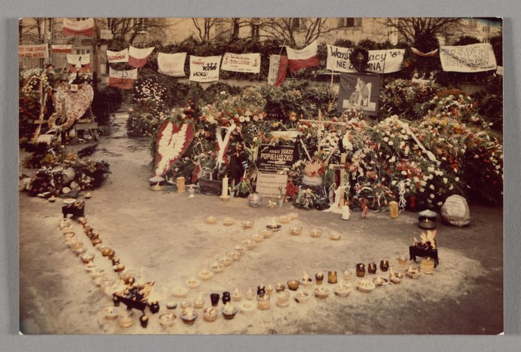 Grób bł. ks. Jerzego Popiełuszki, który został usłany wieńcami i wiązankami, a przed nim ustawiono znicze w kształt litery "V" oraz krzyża
