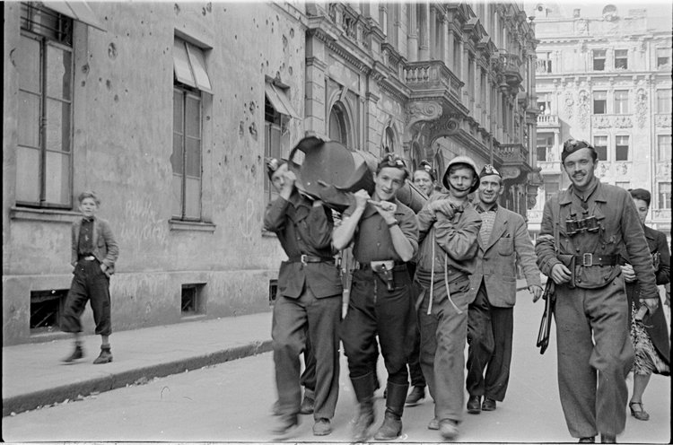 Powstańcy niosący zasobnik zrzutowy na ulicy Wojciecha Górskiego