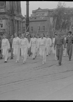 Grupa sportowców maszerująca w pochodzie Krakowskim Przedmieściem