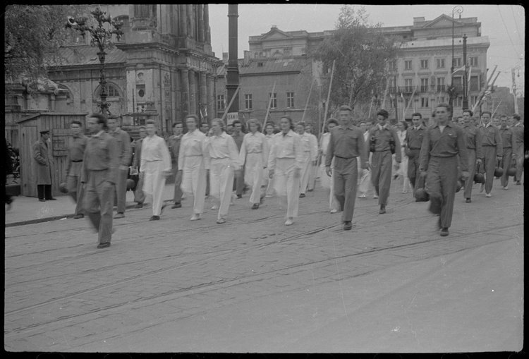 Grupa sportowców maszerująca w pochodzie Krakowskim Przedmieściem