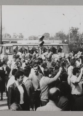 Manifestacja członków NSZZ "SOLIDARNOŚĆ" przechodzących przez ulicę po przejściu dla pieszych, trzymających flagi i chorągiewki biało-czerwone