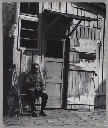 Mężczyzna siedzący przed maglem na podwórzu przy ulicy Konopackiej 6