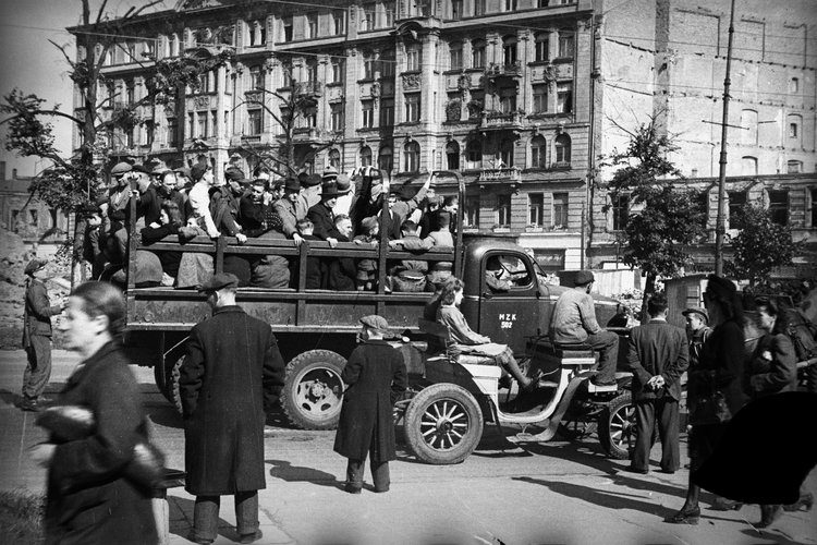Skrzyżowanie ulicy Brackiej z Alejami Jerozolimskimi. Ciężarówka Miejskiego Zakładu Komunikacji zaadaptowana do przewozu ludzi, w tle kamienica Zofii Kiersnowskiej przy ulicy Brackiej 18