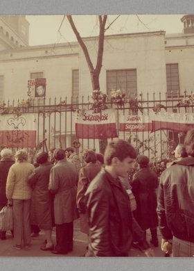 Ogrodzenie kościoła p.w. św. Stanisława Kostki z zawieszonymi flagami i wiązankami kwiatów