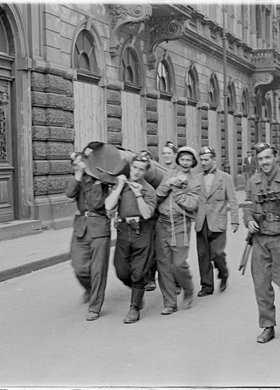Powstańcy niosący zasobnik zrzutowy na ulicy Wojciecha Górskiego