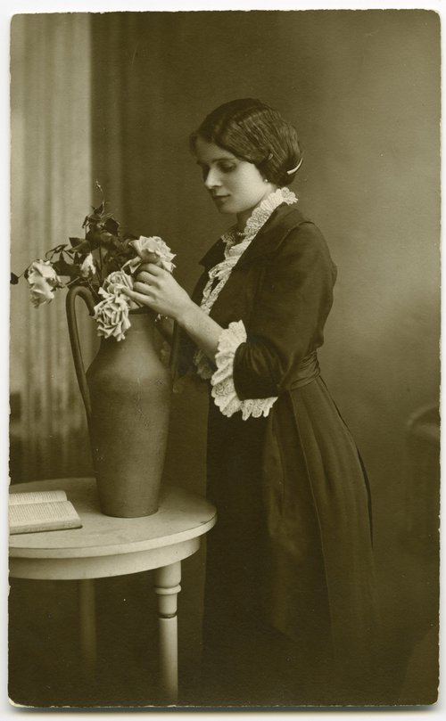 Portret młodej kobiety układającej kwiaty w wazonie
