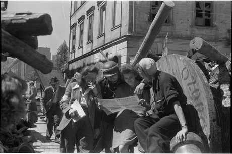 Powstańcy czytający 'Biuletyn Informacyjny' na barykadzie