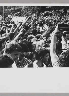 Pogrzeb Grzegorza Przemyka - tłum ludzi idący wokół niesionej trumny, trzymający prawe ręce w górze i dwoma palcami tworzących literę 'V'