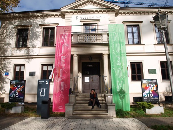 Ewelina Więcek-Bonowska siedząca na schodach do siedziby Muzeum Woli