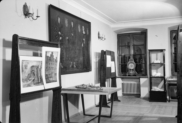 Helena Wrona, muzealna woźna, podczas sortowania potłuczonej porcelany. Obok regał z oczyszczonymi i uporządkowanymi obiektami, 1949
