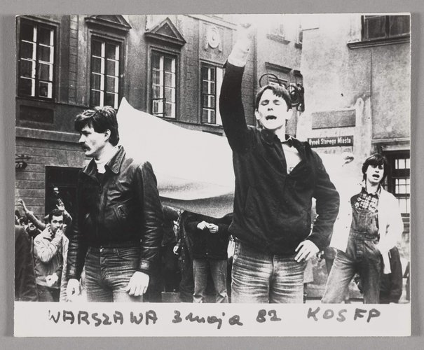 Fotografia czarnobiała przedstawiająca marsz członków NSZZ 'Solidarność' na ulicach Warszawy w dniu 3 maja 1982 r. - ukazuje manifestantów niosących biało - czerwoną flagę, 3 maj 1982
