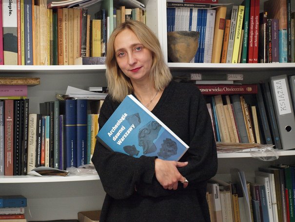 Ewelina Więcek-Bonowska trzymająca publikację z serii Archeologia Dawnej Warszawy